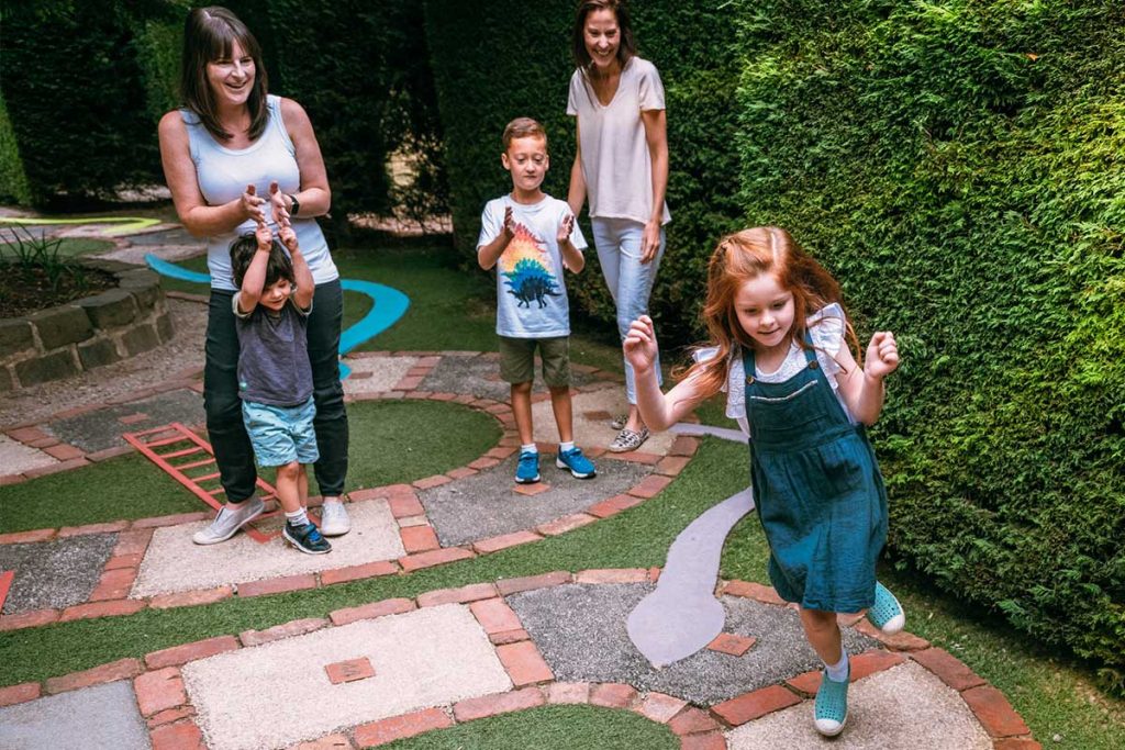 Mums and children enjoying a game of life-sized Snakes & Ladders in the Children's Maze at Enchanted Adventure