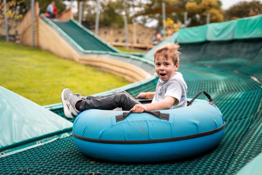 Child smiling on curly Tube Slide activity at Enchanted Adventure